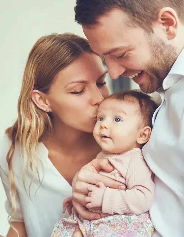 Mother and father holding baby daughter and smiling